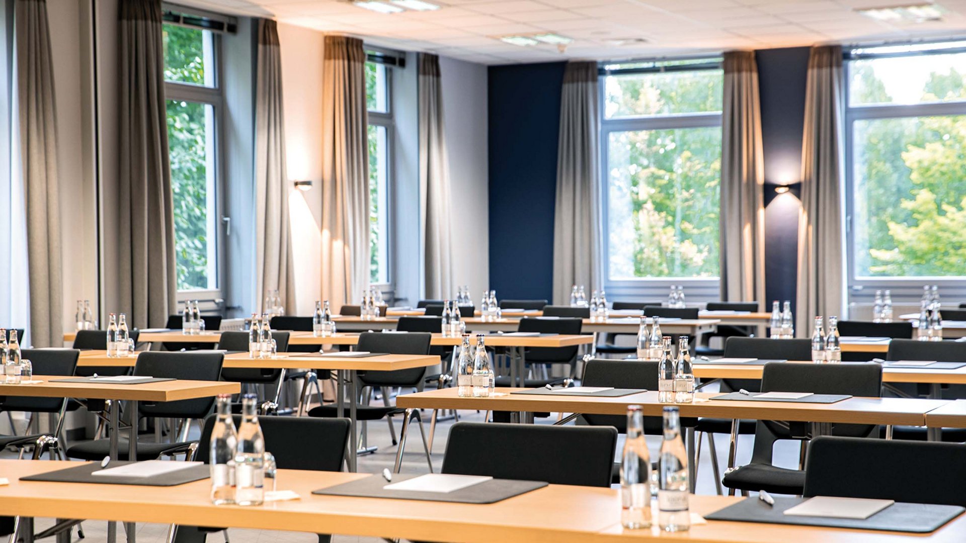 Ihr Tagungshotel in Hannover Moderner Schulungsraum mit Tischen, Stühlen und Wasserflaschen an jedem Platz