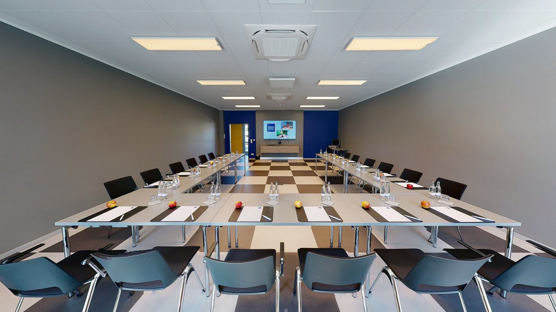 Room 5 Conference room with tables, chairs, water bottles, apples, and notepads