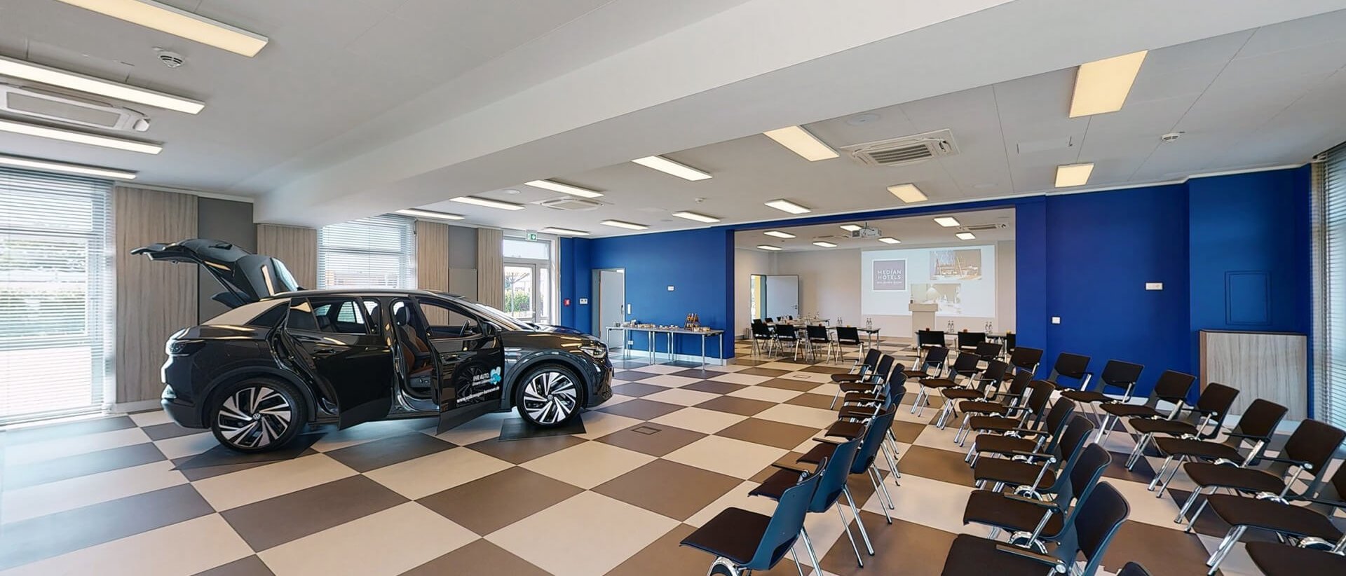Kirchentag 2025 Hannover Konferenzraum mit Elektroauto und mehreren Stuhlreihen vor Projektionswand