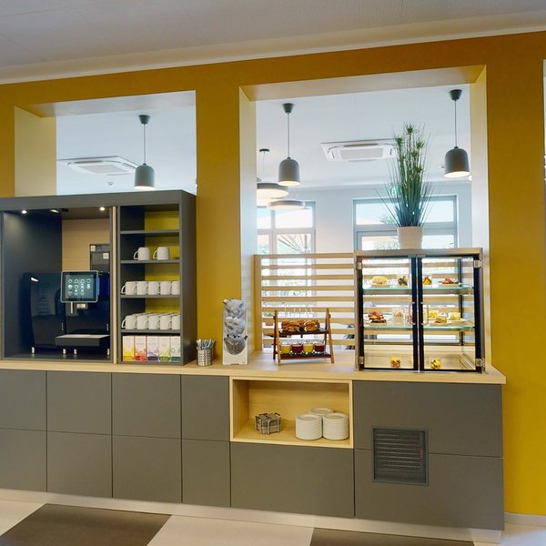 Median Hotel Hannover Lehrte Moderne Cafeteria mit Kaffeemaschine und Auslage für Snacks in hellem Raum