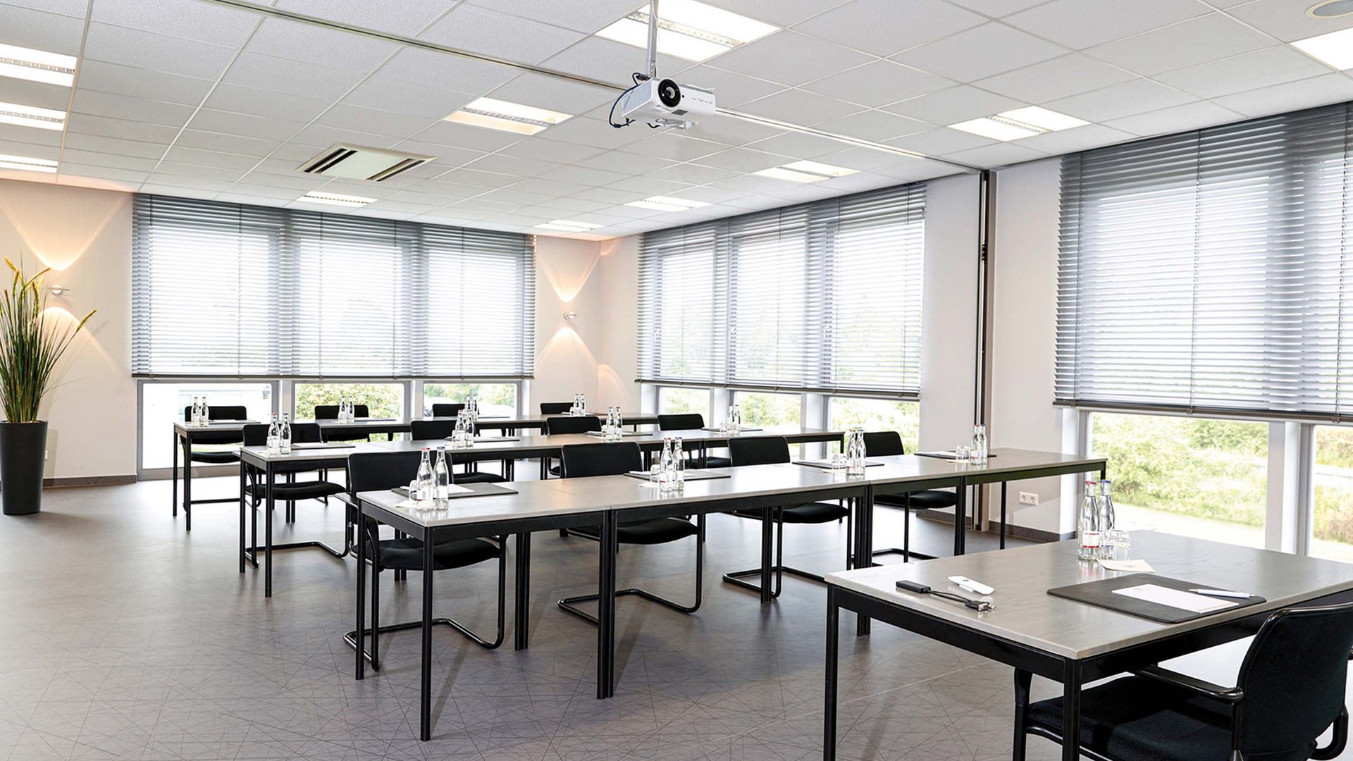 Raum 16-19 Heller Konferenzraum mit Tischen, Stühlen und vorbereitetem Wasser