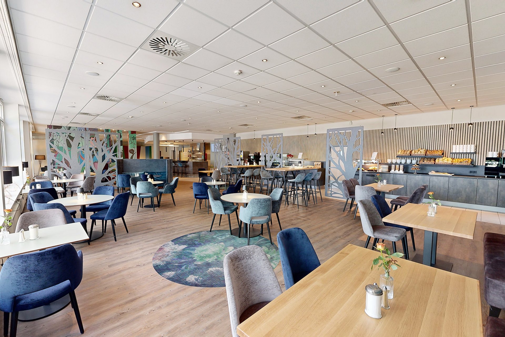 Our hotel at the exhibition centre: the picture gallery Modern café with wooden floor, blue and gray chairs, and buffet in the background