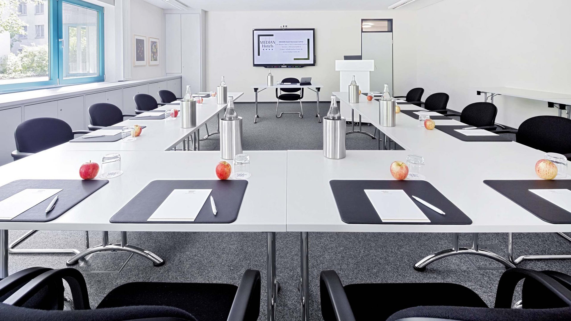Room 10 Bright modern conference room with U-shaped tables and prepared workspaces