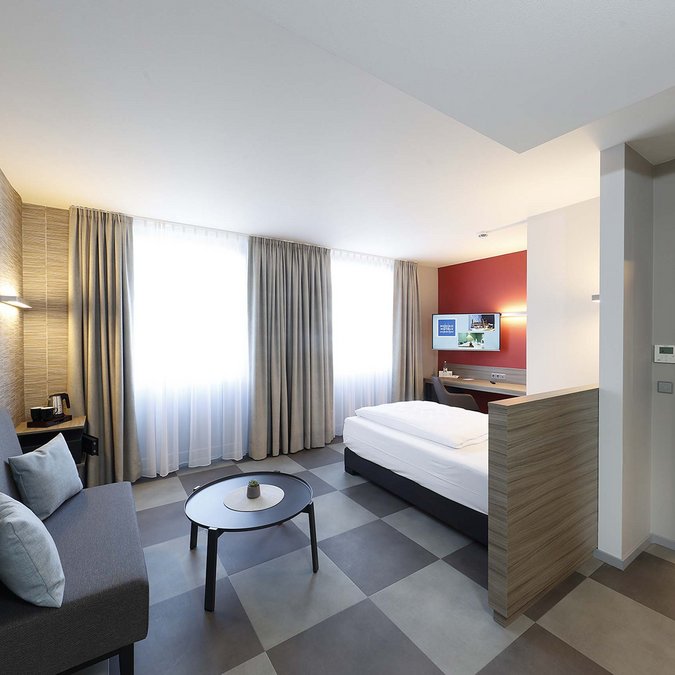 Median Hotel in Lehrte – we provide space Modern hotel room with sofa, bed, and adjacent bathroom