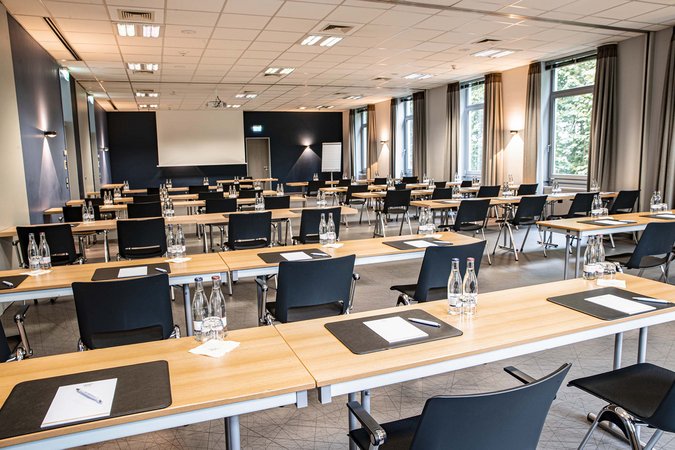Hybrides Tagen in Lehrte Konferenzraum mit Tischen, Stühlen, Wasserflaschen und Schreibmaterialien