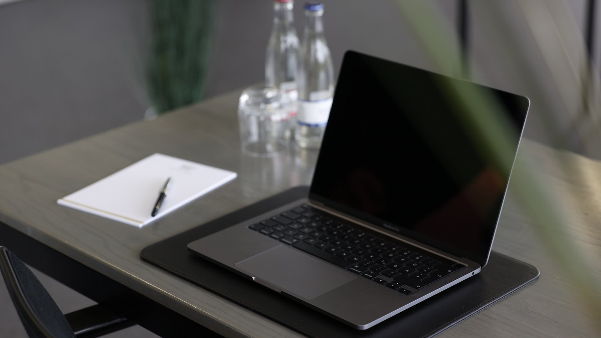 Hotel Median in Lehrte: FAQs Geschlossener Laptop auf Tisch mit Notizblock, Stift und Wassergläsern