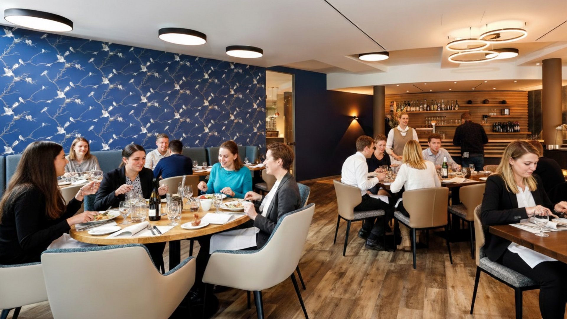 Median Hotel Hannover Lehrte People dining together in a modern restaurant with wood flooring and blue patterned wall