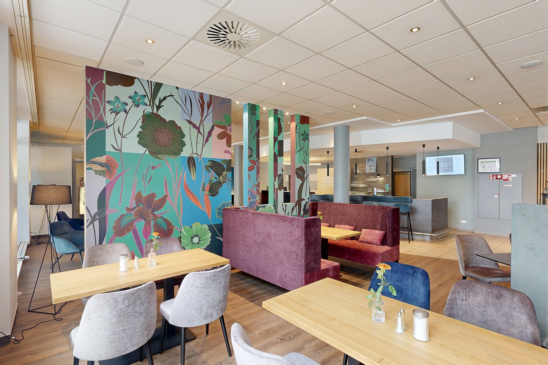 Unser Hotel an der Messe: die Bildergalerie Modernes Restaurant mit floraler Wanddekoration und gemütlichen Sitzbereichen
