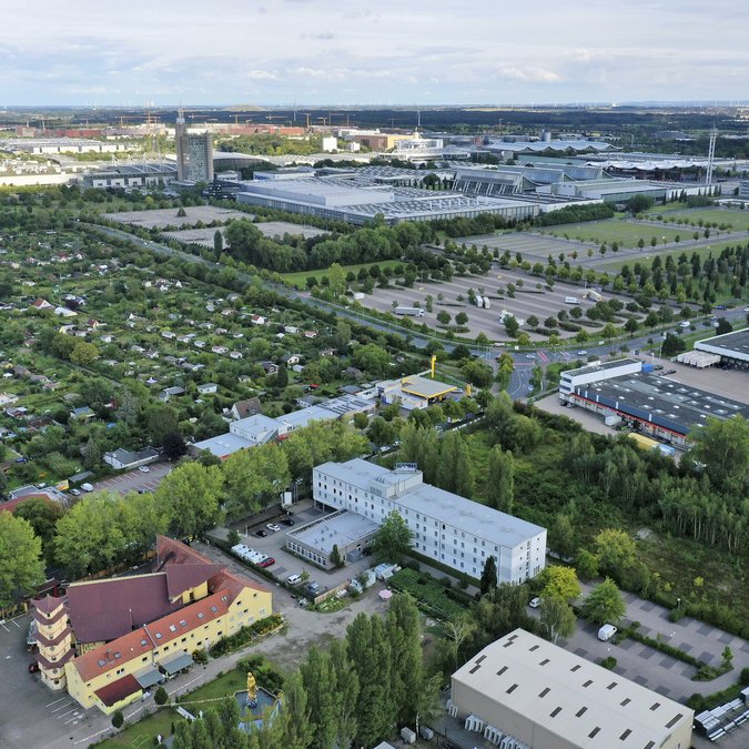 Median Hotel Hannover Messe: Wir geben Raum Luftaufnahme eines Gewerbegebiets neben einem Garten- und Wohngebiet bei Tageslicht