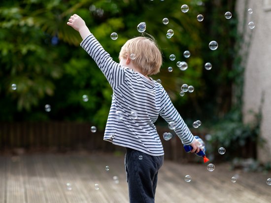 Median Hotel Messe Hannover – der Newsblog Kind mit gestreiftem Shirt spielt mit Seifenblasen im Garten