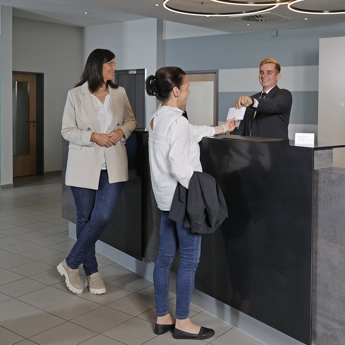 Median Hotels: Stellenangebote für Hannover und Lehrte Zwei Frauen checken an der Hotelrezeption ein, Concierge übergibt Schlüsselkarte