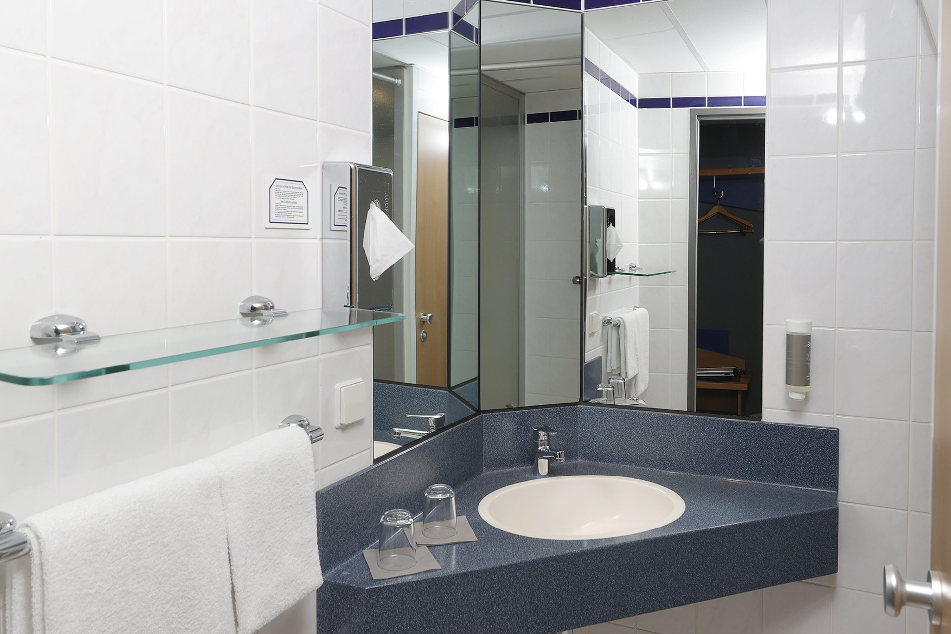 Our hotel at the exhibition centre: the picture gallery Clean bathroom with sink, towels, and corner mirror