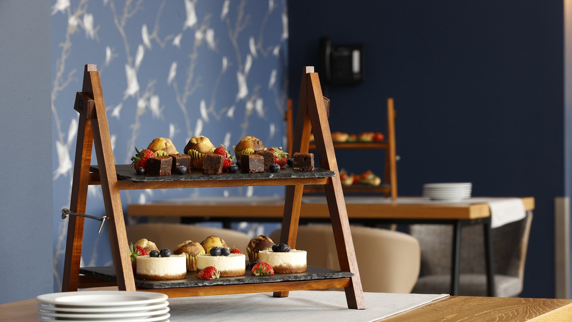 Die modernsten Tagungsräume in Hannover Zweistöckiges Holztablett mit Kuchen und Beeren auf einem Holztisch im Café