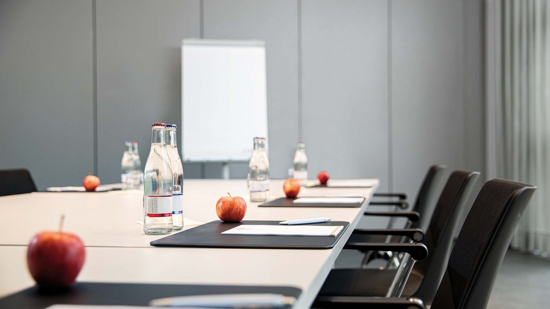 Konferenztisch mit Äpfeln, Wasserflaschen und Schreibmaterial in einem Besprechungsraum