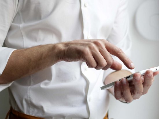 Median Hotel Messe Hannover – der Newsblog Person bedient Smartphone mit einer Hand, trägt weißes Hemd