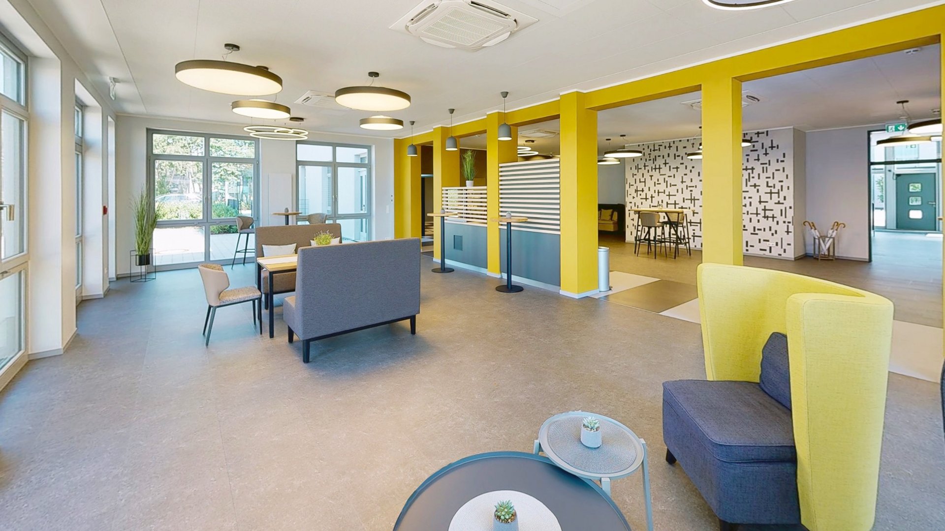 Ihr autarker und exklusiver Tagungsbereich: Ihr Hotel im Hotel Moderner Aufenthaltsraum mit gelben Säulen und Sitzbereichen