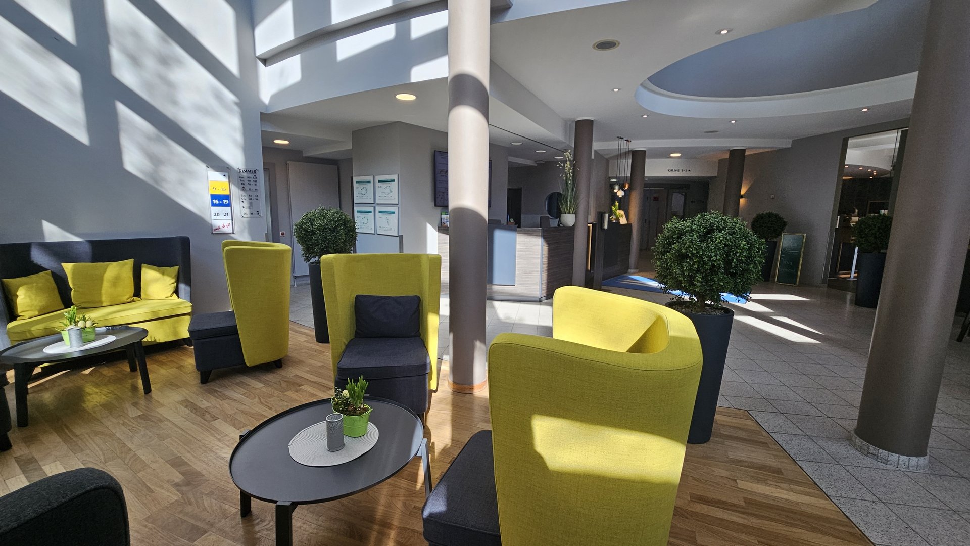 Median Hotel Hannover Lehrte Modern waiting area with yellow chairs and plants in daylight