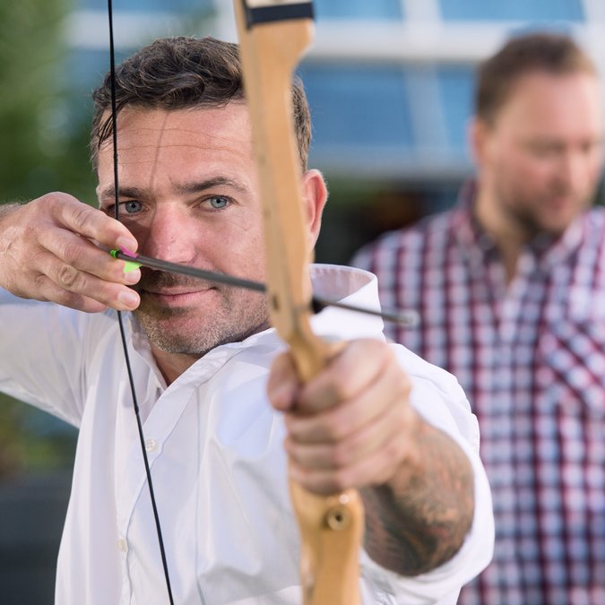 Teambuilding in Hannover und Umgebung Mann zielt mit einem Bogen beim Bogenschießen im Freien