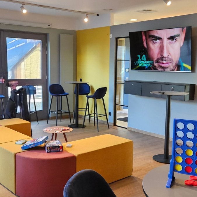 Teambuilding in Hannover und Umgebung Moderne Lounge mit gelben Sitzmöbeln, Spieltisch, Dartautomat und Fernseher an der Wand