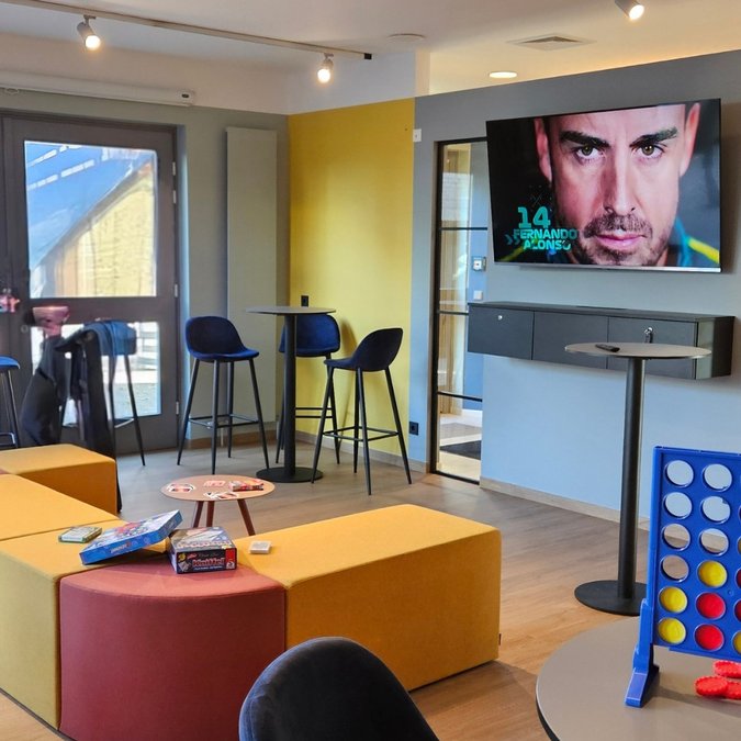 Teambuilding in Hannover und Umgebung Moderne Lounge mit gelben Sitzmöbeln, Spieltisch, Dartautomat und Fernseher an der Wand
